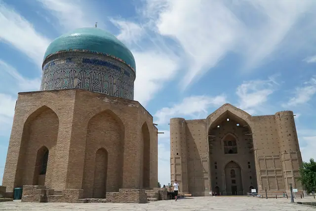 Turkestan: rabiga Sultan Begim mausoleum with turquoise dome and the Yasawi portal behind