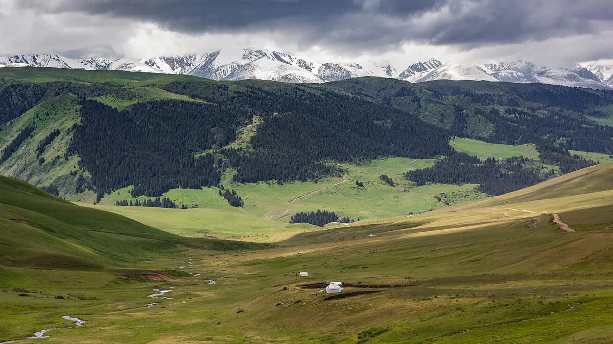 Assy Plateau: wide jailau valley of the Assy plateau with a white yurt and snowy peaks